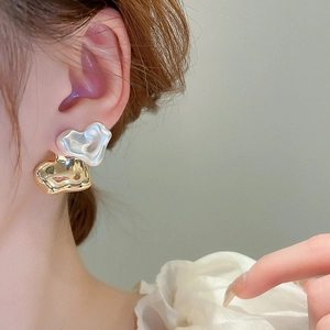 Elegant gold and pearly white irregular heart stud earrings on a female model