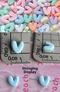Macro detail of 1cm macaron resin letter beads for DIY necklaces with threading demo