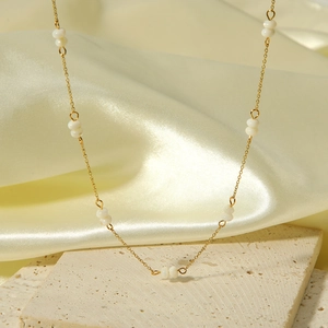 Detailed shot of golden beaded necklace on stone with silk fabric backdrop
