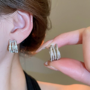 Macro shot of multi-layer crisscross silver hoop earrings with shimmering cubic zirconia