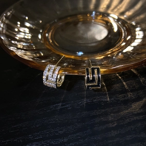 Détails de boucles d'oreilles C dorées avec cristaux et motif grec en émail noir brillant