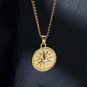 Détail d'un collier pendentif boussole plaqué or 18k sur un fond en pierre sombre