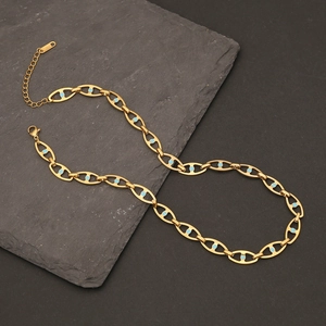 Detail of gold Cuban chain with blue accents on dark slate stone background