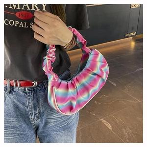 Detailed view of rainbow gradient pleated shoulder bag worn by model in casual setting
