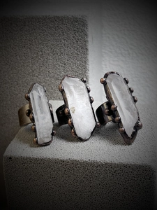 Close-up of three vintage raw white crystal rings with bronze metal edges on stone