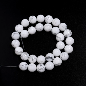 Macro shot of white turquoise beads with grey marble veins on black background