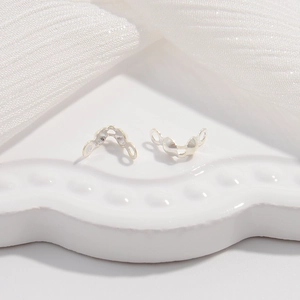 Macro view of S925 sterling silver folding crimp ends for jewelry making on ceramic tray
