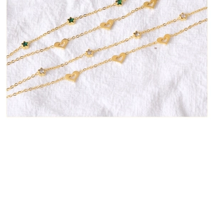 Macro view of gold-plated hollow heart and star charms with green zircons on chains