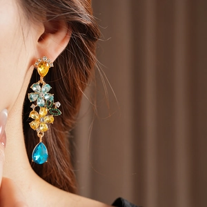 Close-up of vintage floral drop earrings with yellow and blue rhinestones on a model