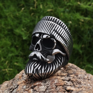 Close-up of a vintage biker skull ring with a beanie and beard on a rustic wood base