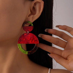 Close-up of geometric resin earrings with burgundy and green marble texture on model