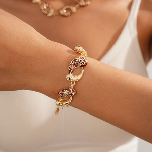 Detailed shot of golden flower bracelet with red enamel and white zircon on wrist