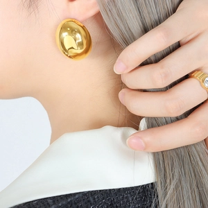 Minimalist chunky gold oval stud earring worn by an elegant model for daily fashion style.