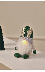 Detail of a lighted Christmas gnome with gold antlers and warm glowing nose on a table