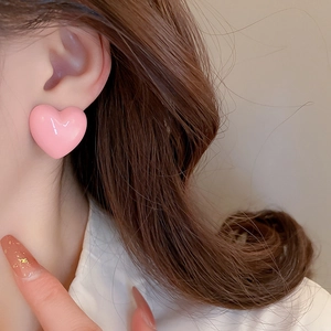 Close-up of model wearing pink heart-shaped acrylic stud earrings with a smooth finish
