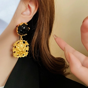 Detailed view of vintage gold lion head earrings with a black gemstone on model