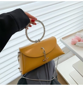 Close-up of yellow evening bag featuring a unique sparkling rhinestone ring handle