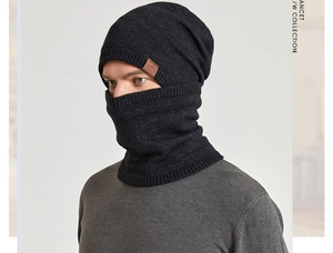Close-up of black knitted winter beanie with brown leather patch and matching neck warmer