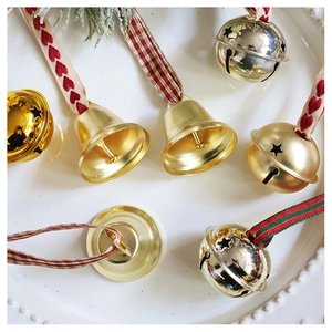 Close-up of champagne gold star-cut bells with red heart ribbons in a white ceramic dish
