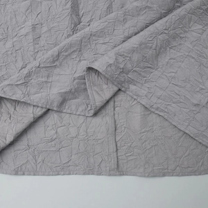 Détail macro du tissu plissé gris montrant la texture fine et les coutures de l'ourlet
