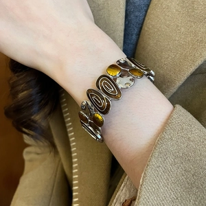 Detail of vintage elastic bracelet featuring brown enamel inlays on silver alloy links