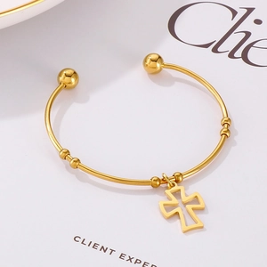 Detailed macro shot of the golden stainless steel bangle with a hollow cross pendant