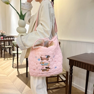 Pink quilted shoulder bag with dachshund embroidery shown on a model in a warm setting