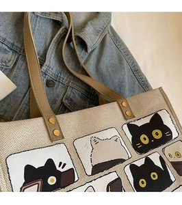 Detail of beige canvas cat tote bag with brown PU straps on casual denim jacket