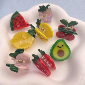Assorted cute acetate fruit hair clips including strawberry and peach on a ceramic plate
