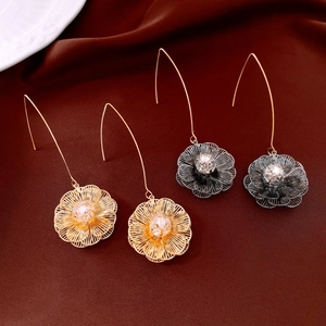 Vue macro de boucles d'oreilles fleurs évidées avec zircon sur tissu de soie marron