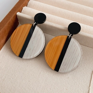 Détails de boucles d'oreilles rondes avec texture bois et résine sur du velours beige