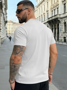 Rear view of a slim-fit white Henley shirt on a model in a European street setting
