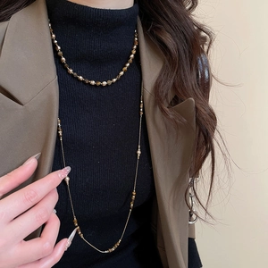 Close-up of layered tiger eye stone beaded necklaces on a model in olive green suit