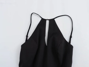 Détail de robe moulante noire sexy avec fines bretelles licou et découpe sur le buste