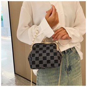 Close-up of checkerboard crossbody bag with pearl strap and gold metal clasp detail