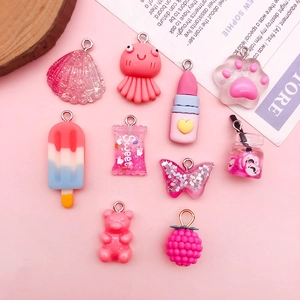 Flat lay of pink resin charms featuring cute animals, candies, and fruit shapes for DIY crafts