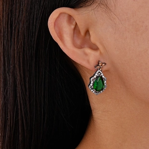 Close-up of model wearing vintage pear-cut emerald earrings with zirconia accents