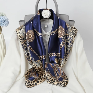 Detail of navy silk scarf with gold chains and leopard print tied on a white shirt collar
