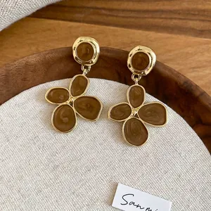 Détail de boucles d'oreilles fleur vintage avec émail marron et pétales en métal doré