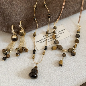 Detail of tiger eye stone jewelry set with tassel earrings and gourd pendant on fabric