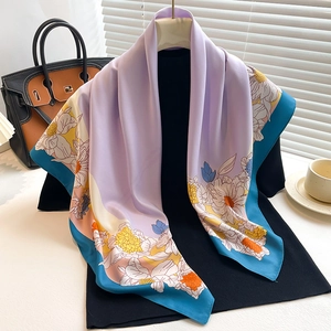 Elegant purple silk scarf with blue border and floral print draped over a model