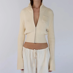 Detail of slim-fit cream knit cardigan featuring vertical ribs and metal zipper closure