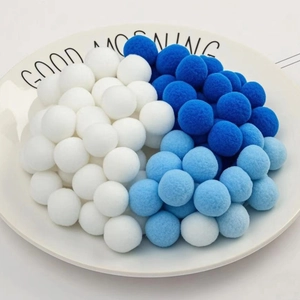 Close-up of fluffy white and blue pom poms in a Good Morning ceramic tray for DIY decor
