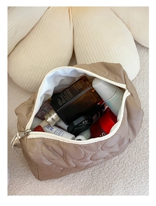 Vue de dessus d'une trousse à maquillage matelassée beige montrant sa grande capacité