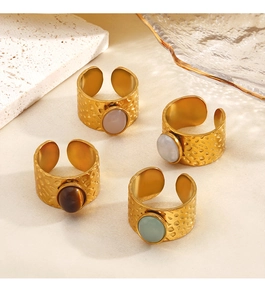 Macro shot of hammered gold rings with assorted gemstone inlays on textured stone