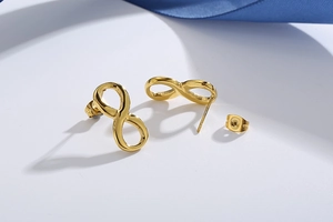 Detailed close-up of golden infinity symbol stud earrings on a clean white background