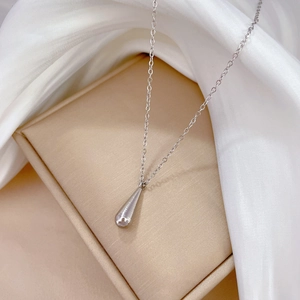 Detail of silver teardrop pendant on beige jewelry box with elegant silk background
