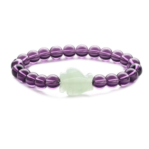 Close-up of translucent purple beads and green carved stone on an elastic beaded bracelet