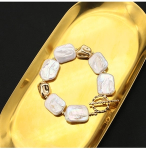 Macro detail of Baroque pearl bracelet with golden irregular beads and toggle clasp