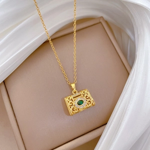 Detail of luxury gold necklace with green gemstone pendant on white silk fabric